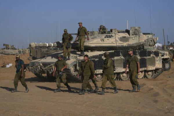 Israeli soldiers walk in a staging area for their tanks near the Gaza border in southern Israel, . Picture: AP Photo/Tsafrir Abayov Israeli soldiers walk in a staging area for their tanks near the Gaza border in southern Israel, . Picture: AP Photo/Tsafrir Abayov